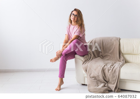 Young attractive woman dressed in beautiful colorful pajama posing as a model in her living room. Comfortable sleepwear, home relaxation and female fashion concept. Young attractive woman dressed in beautiful colorful pajama posing as a model in her living room. Comfortable sleepwear, home relaxation and female fashion concept. 64087032