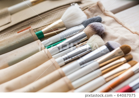 Makeup, beauty and cosmetics concept - Set of make-up brushes in a light case. 64087075