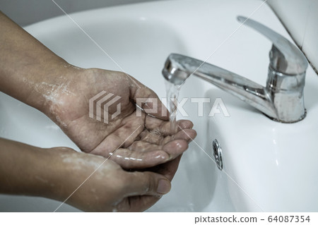 Woman washing hands under the water tap in 64087354