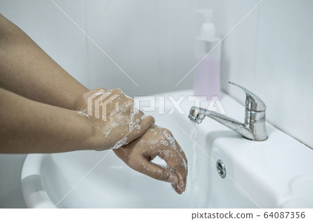 Woman washing hands under the water tap in 64087356
