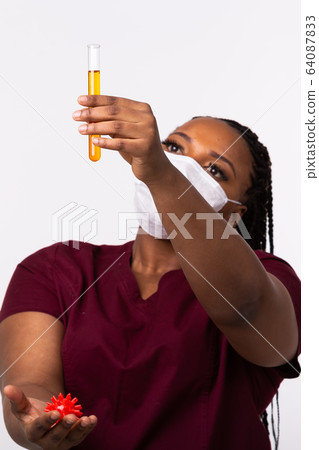 Covid-19, Vaccine development , outbreak and medicine concept - Doctor in medical protective mask holding a model of coronavirus and test tube on white background with copy space. 64087833