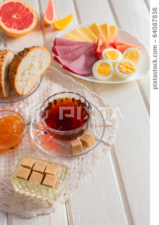 Fresh delicious breakfast with soft boiled egg, cheese, ham fresh bread and cup coffee or tea on light wooden background. 64087836
