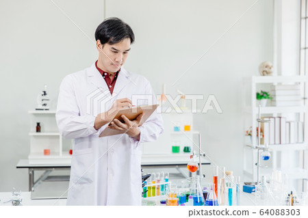 Asian Male Scientist Doctor pay attention working in lab hand taking note or research  64088303