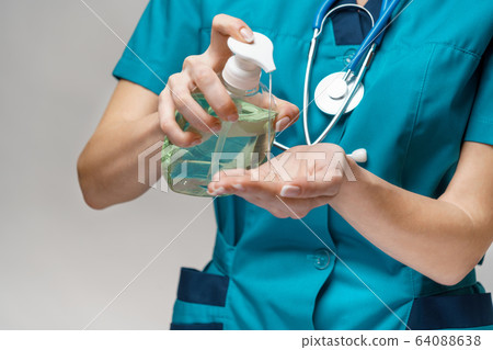 medical doctor nurse wearing protective mask - holding sanitizing spray or gel or liquid soap 64088638