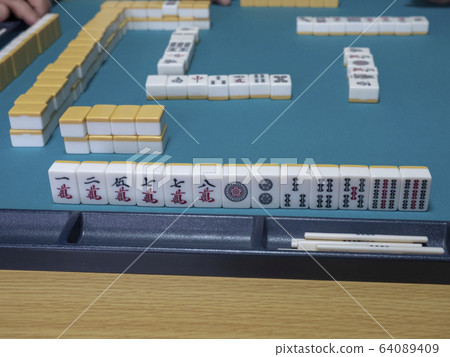 Hand tiles and reach sticks arranged on the mahjong table 64089409