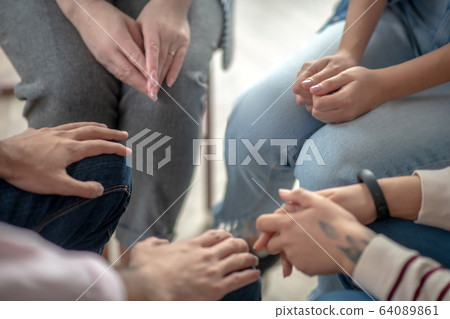 Close up picture of people sitting in a circle close to each other Close up picture of people sitting in a circle close to each other 64089861