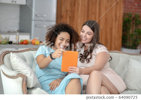 Two young girlfriends taking selfie on tablet at home. 64090725