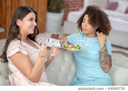 Sad woman with vegetable salad and cheerful with a chocolate bar. Sad woman with vegetable salad and cheerful with a chocolate bar. 64090750