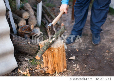Man chopping wood in the backyard. Lumberjack cuts logs 64090751