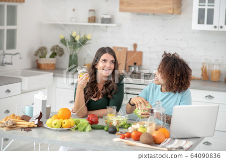 Two girlfriends preparing vegetarian food and communicate. Two girlfriends preparing vegetarian food and communicate. 64090836