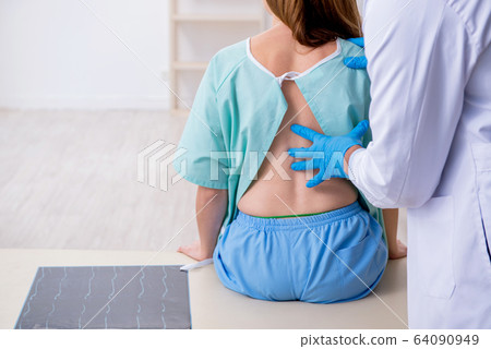 Young back injured woman visiting male doctor chiropractor 64090949