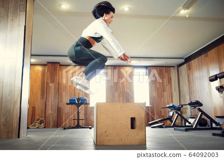 Shot of young woman working out with a box at the gym. Female athlete box jumping at a functional training gym 64092003