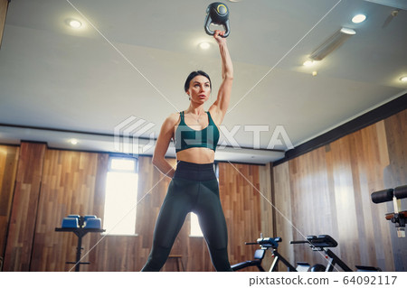 Young adult fitness woman doing swing exercise with a kettlebell as a part of a fitness workout 64092117