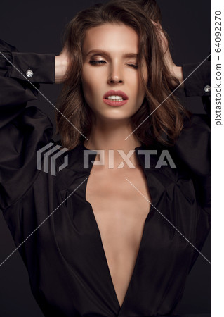Portrait of beautiful brunette woman in black dress with one eye closed. Fashion photo, 64092270