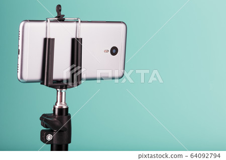 The smartphone is mounted on a tripod as a The smartphone is mounted on a tripod as a 64092794