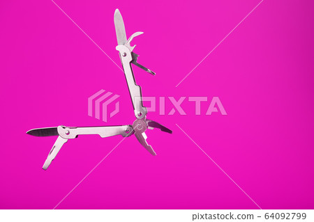 Multitool is a multi-functional tool on a pink Multitool is a multi-functional tool on a pink 64092799