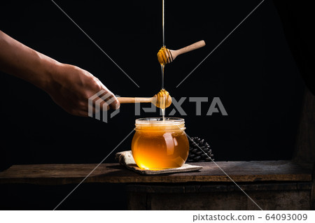 Honey in a glass jar,Scoop the honey in a glass 64093009