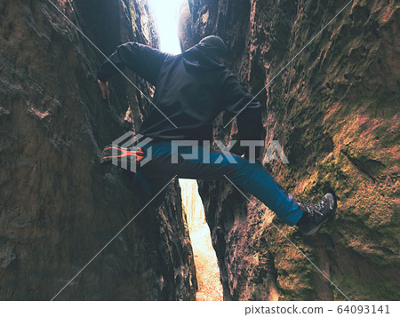 Man climbing in thin distance between two rocks. Man climbing in thin distance between two rocks. 64093141