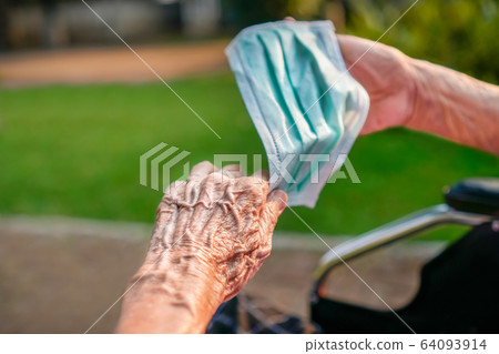 Elderly woman wearing a mask to protect from 64093914