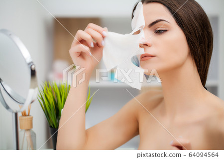Cute woman in bathroom doing cosmetic procedure for facial skin care 64094564