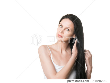 Natural beauty, caucasian beautiful female face with long loose black hair and bare shoulders, close up. Woman tilts her head to the side and fix her curls, isolated on white. Natural beauty, caucasian beautiful female face with long loose black hair and bare shoulders, close up. Woman tilts her head to the side and fix her curls, isolated on white. 64096389