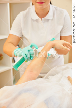 depilation and beauty concept - procedure of hair removing on hand woman with sugar paste or wax honey and blue gloves hand depilation and beauty concept - procedure of hair removing on hand woman with sugar paste or wax honey and blue gloves hand 64096470