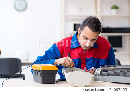 Young repairman repairing air-conditioner at warranty center Young repairman repairing air-conditioner at warranty center 64097465
