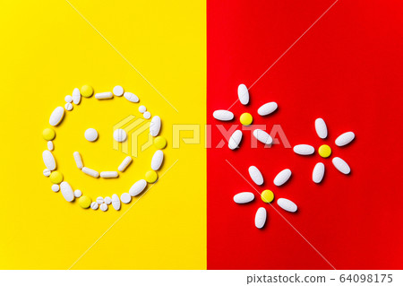 Colored pills, tablets and capsules on a red and yellow background - history of treatment, prevention of pandemic 64098175