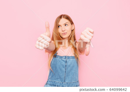 A young attractive woman makes a good-bad sign. A young attractive woman makes a good-bad sign. 64099642