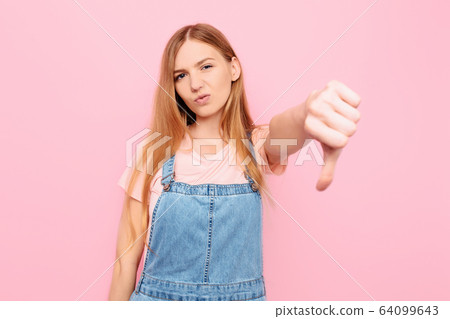 Dislike, discontented girl making a thumbs down Dislike, discontented girl making a thumbs down 64099643