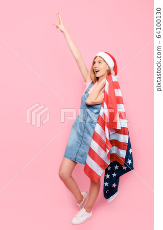woman in a Santa hat holds an American flag and woman in a Santa hat holds an American flag and 64100130