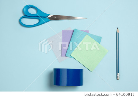 Sticker papers, scissors, pen. Monochrome stylish composition in blue color. Top view, flat lay. Sticker papers, scissors, pen. Monochrome stylish composition in blue color. Top view, flat lay. 64100915