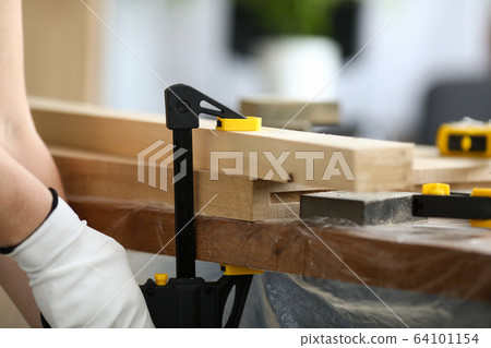 Woodworker fastens wooden parts on workbench 64101154