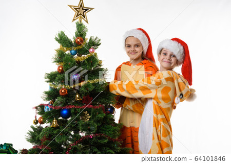Two girls at the Christmas tree looked into the 64101846