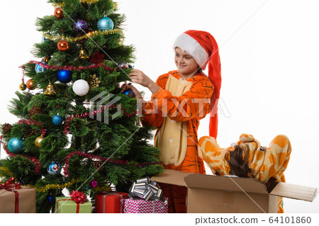 One girl hangs a ball on the Christmas tree, the 64101860