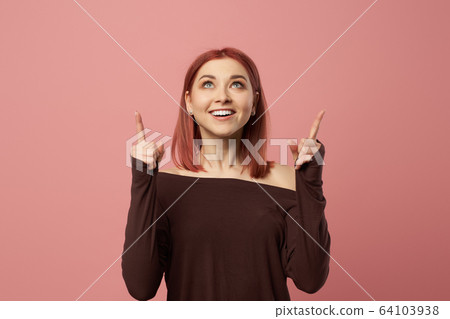 Happy ginger girl with gray eyes pointing up 64103938