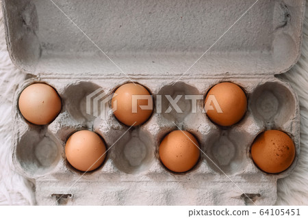 Raw brown eggs in tray alternating with empty spaces. 64105451