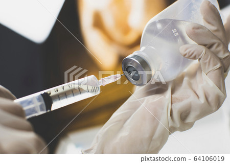 Anesthesiologist Doctors hand inject syringe into normal saline solution (NSS) bottle. 64106019