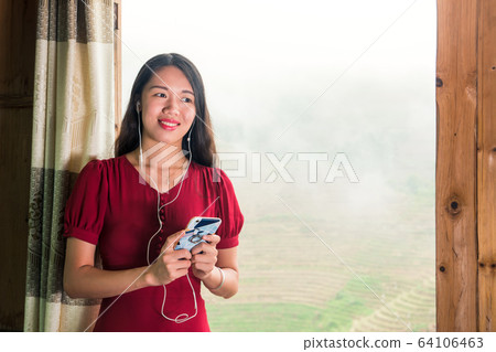woman using phone and listening music by the 64106463