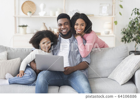 Smiling Black Parents And Little Daughter Posing With Laptop At Home Smiling Black Parents And Little Daughter Posing With Laptop At Home 64106886