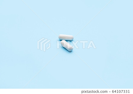 Two medicine capsules on blue background. 64107331