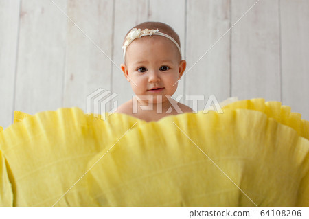 One year old girl sitting in handmade paper green cabbage. Portrait.  64108206
