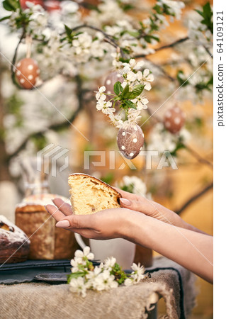 Traditional russian Easter. Woman hands take Orthodox paskha, kulich cakes on table. 64109121