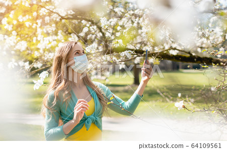 Woman enjoying the spring blossom despite the Coronavirus crisis 64109561