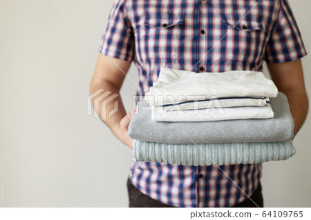 Man holding stack of clean laundered clothes Man holding stack of clean laundered clothes 64109765