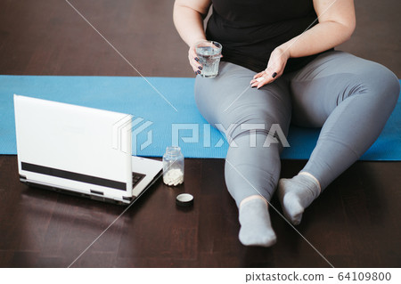 Fat obese woman with pills between home workout Fat obese woman with pills between home workout 64109800