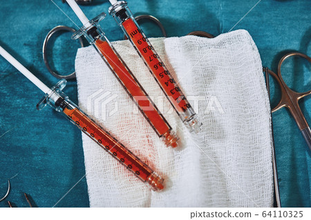 Greasy syringes for transplanting fat against a background of blue sterile tissue on a swab. Plastic surgery. Greasy syringes for transplanting fat against a background of blue sterile tissue on a swab. Plastic surgery. 64110325