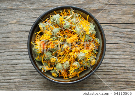 Healthy calendula flowers. Bowl of dry marigolds Healthy calendula flowers. Bowl of dry marigolds 64110806