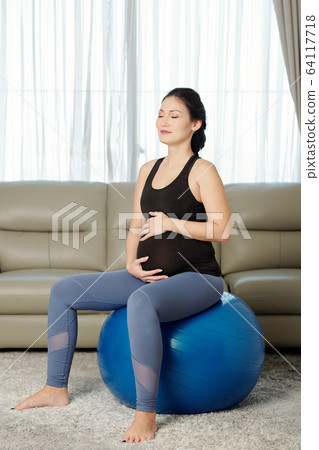 Pregnant woman sitting on fitness ball Pregnant woman sitting on fitness ball 64117718