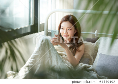 Young woman window bedroom relaxing morning call Young woman window bedroom relaxing morning call 64119492
